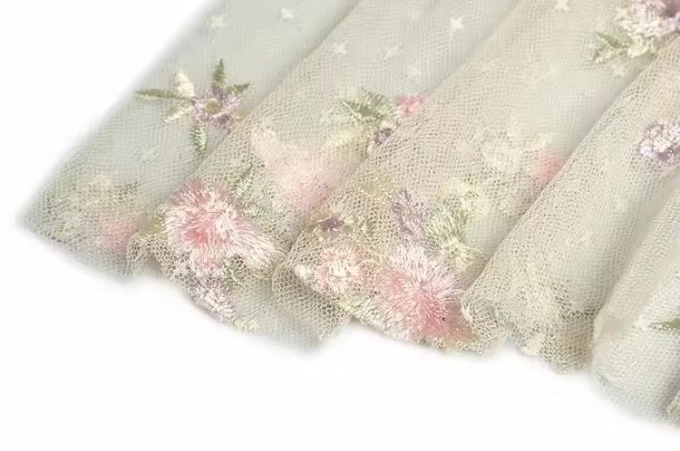 
                  
                    Light green fabric with floral embroidery on a white background
                  
                
