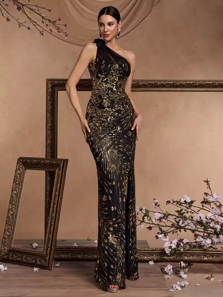 
                  
                    Woman in a black and gold sequin dress standing in front of decorative mirrors and floral arrangements.
                  
                